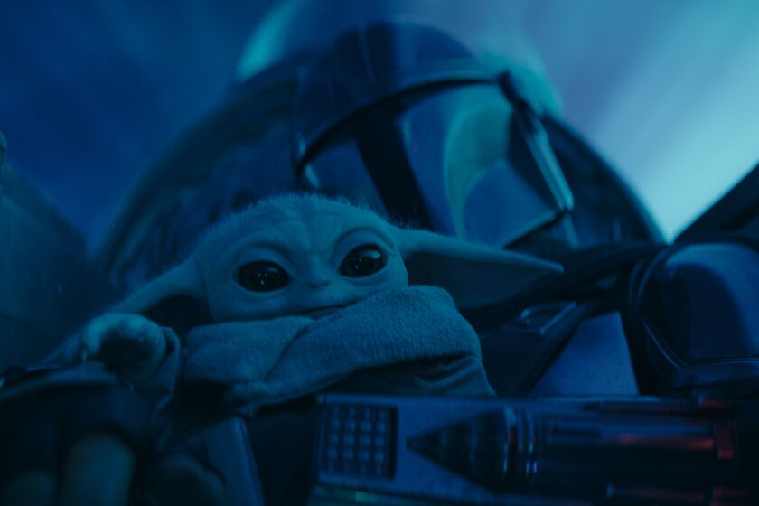 an adorable alien toddler being held by his helmeted father in the cockpit of a spaceship  