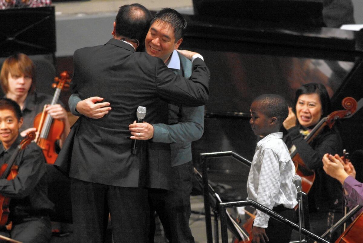 Matt Huang gets a hug from Pastor Greg Waybright on the family's return to their church, Lake Avenue Church in Pasadena.