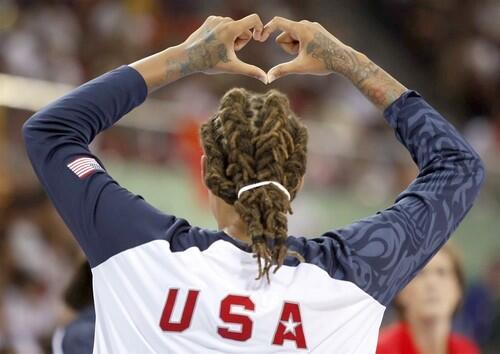 U.S. women's basketball player Seimone Augustus flashes a heart sign while on the sidelines.