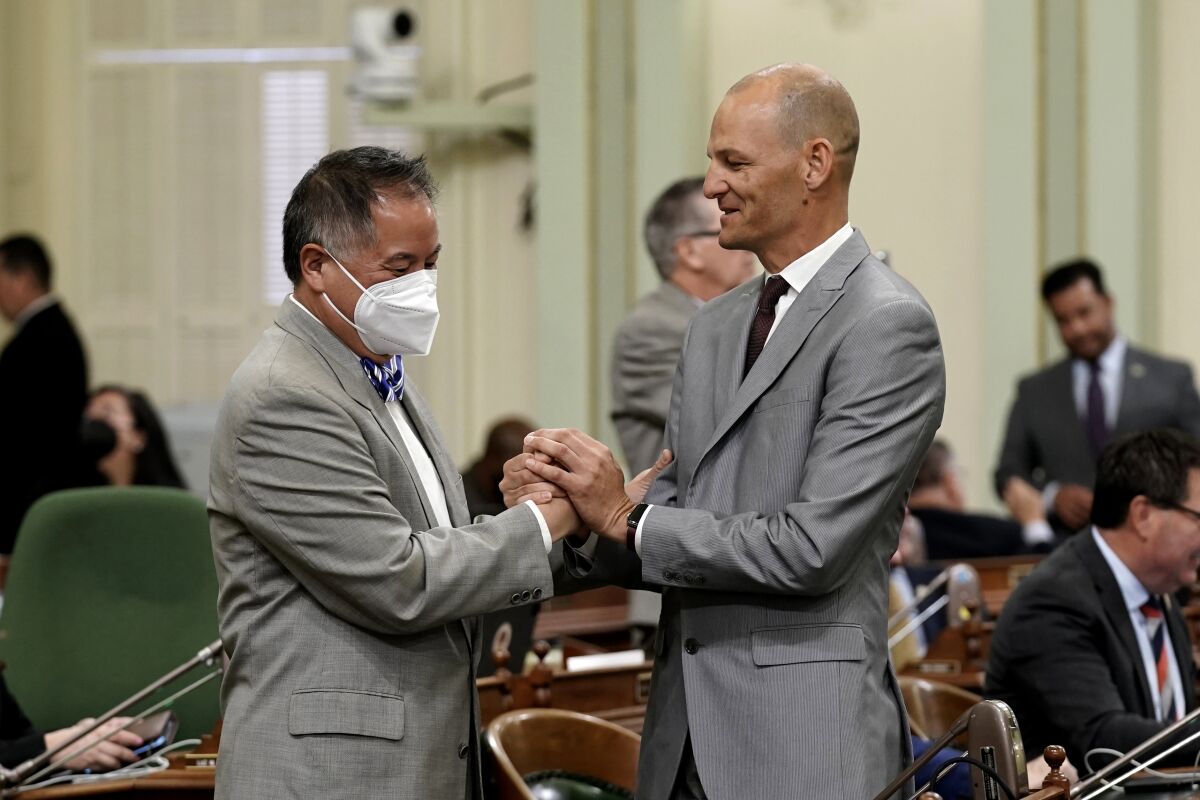 Assemblyman Phil Ting, D-San Francisco, chair of the Assembly budget committee, left, is congratulated by fellow Democratic Assemblyman Kevin McCarty, of Sacramento, after the Assembly approved the state budget bill, at the Capitol in Sacramento, Calif., Monday, June 13, 2022. California Lawmakers approved their own version of a $300 billion operating budget over the objections of Gov. Gabin Newsom, highlighting the disagreements among Democrats about how to spend a second-breaking surplus.(AP Photo/Rich Pedroncelli)