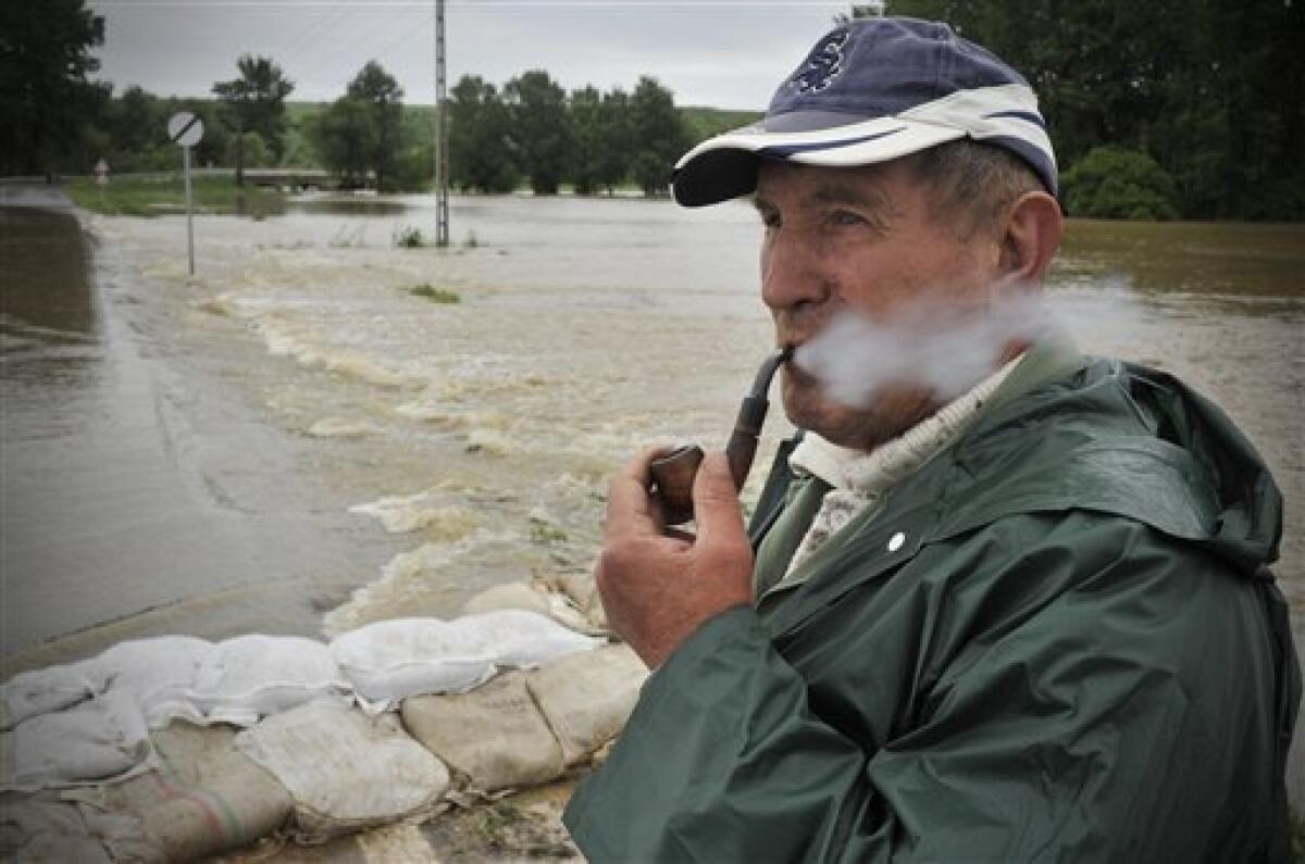 A Hungarian farmer smokes his pipe beside an over-flooded road near the village of Kiskinizs, northeastern Hungary, Tuesday, May 18, 2010. Several swollen rivers causing floods throughout Hungary, while roads remain closed due to heavy rains. Heavy rains that began in central Europe last weekend also are causing flooding in areas of Poland, Slovakia and the Czech Republic, with rivers bursting their banks and inundating low-lying homes and roads, and cutting off villages. (AP Photo/Bela Szandelszky)
