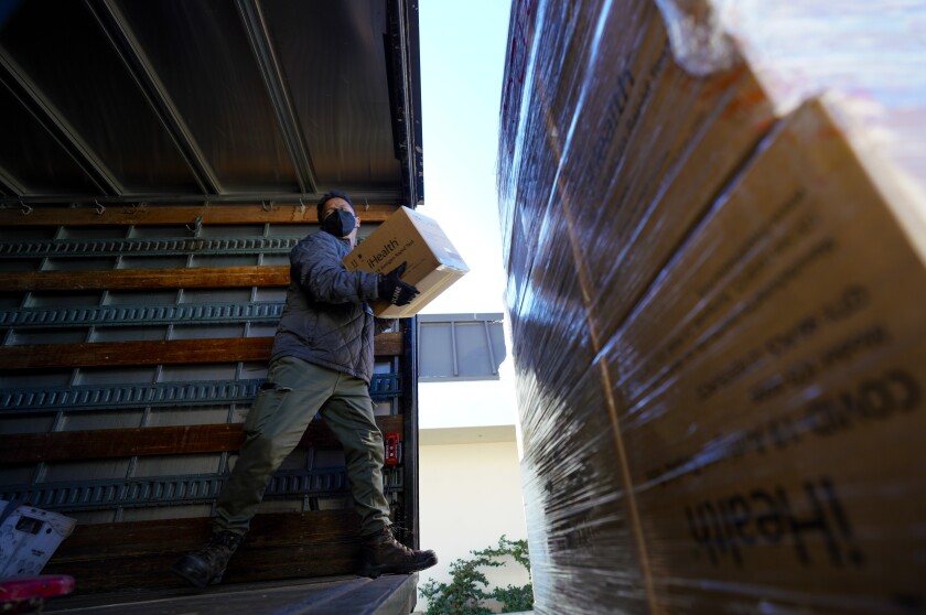 Carl Pino loads the district's shipment of at-home COVID-19 test kits.