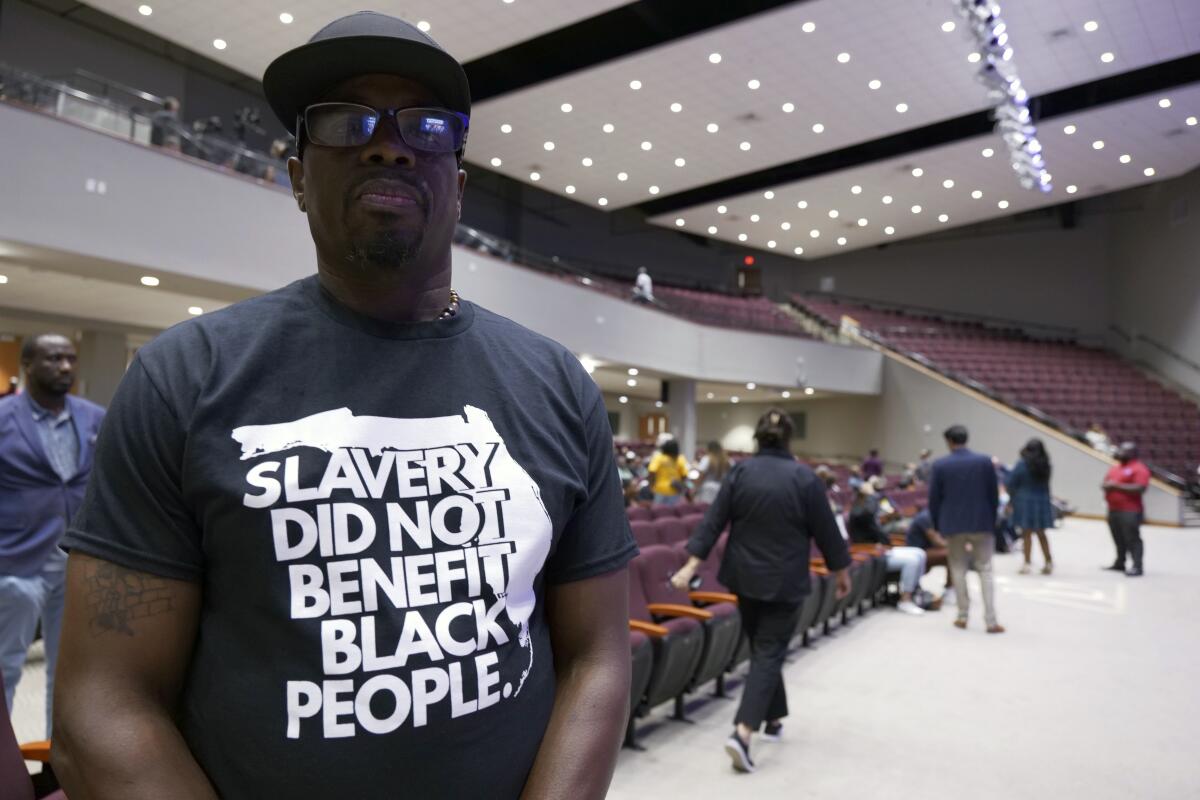 A man at a forum wears a T-shirt reading "Slavery did not benefit Black people."