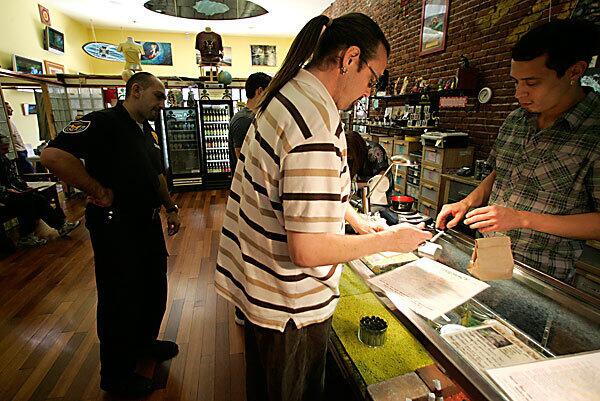 Under the watchful eye of security guard Edgar Gasparyan, a customer buys medical marijuana at Farmacy in West Hollywood. "We're just part of the community," says JoAnna LaForce, the pharmacist who runs the store.