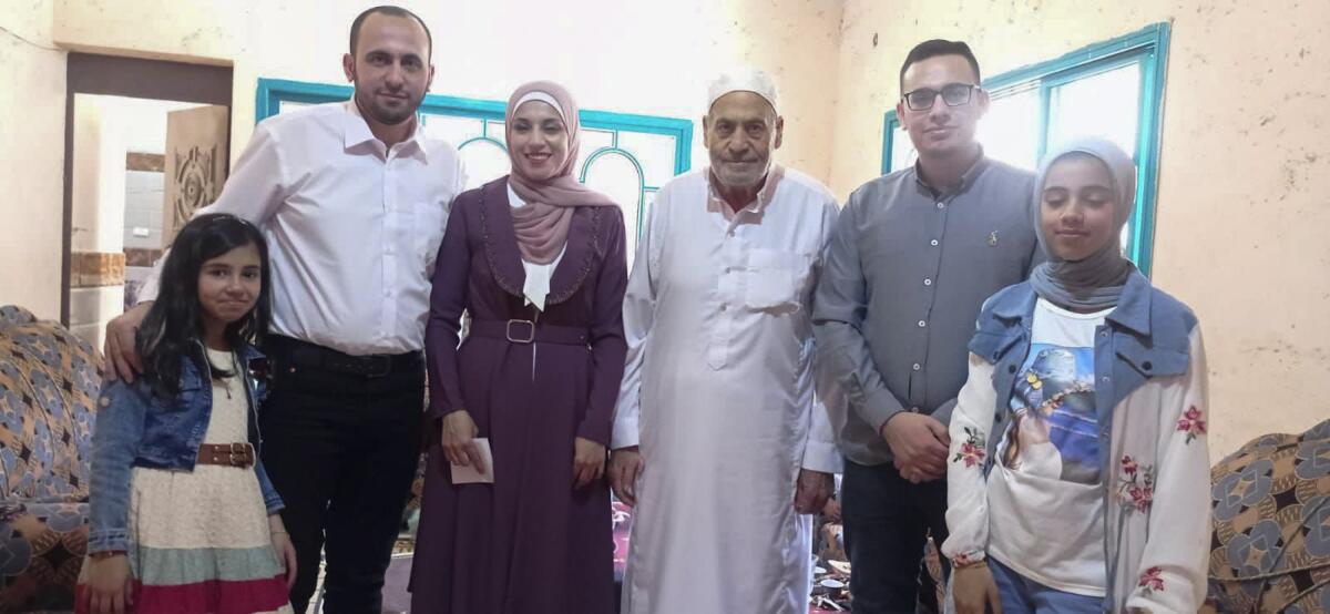 Six people, several generations, pose for a photo in a home in Deir al Balah, Gaza.