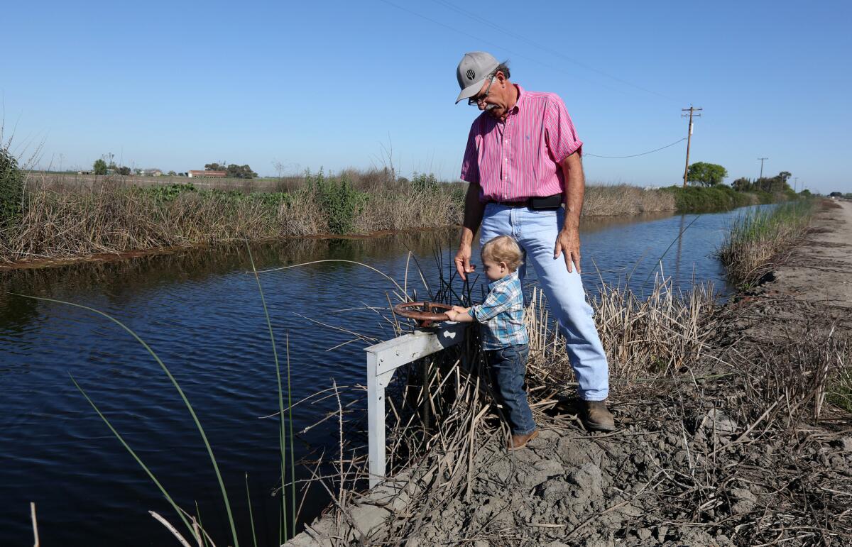 Farmer Rudy Mussi watches as his grandson Lorenzo tries to turn a water valve on his almond orchard in the Sacramento-San Joaquin River Delta near Stockton.
