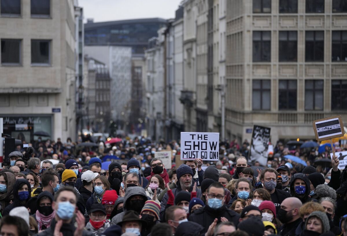 At a demonstration, a man holds a sign that reads 'The show must go on'