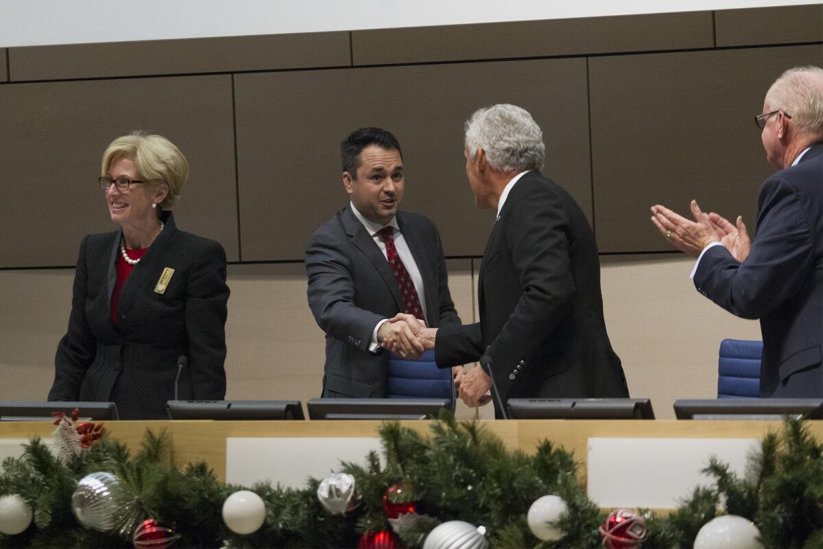 New Newport Beach Mayor Kevin Muldoon, center, is congratulated by council members as he takes his seat at Newport Beach City Hall on Tuesday.