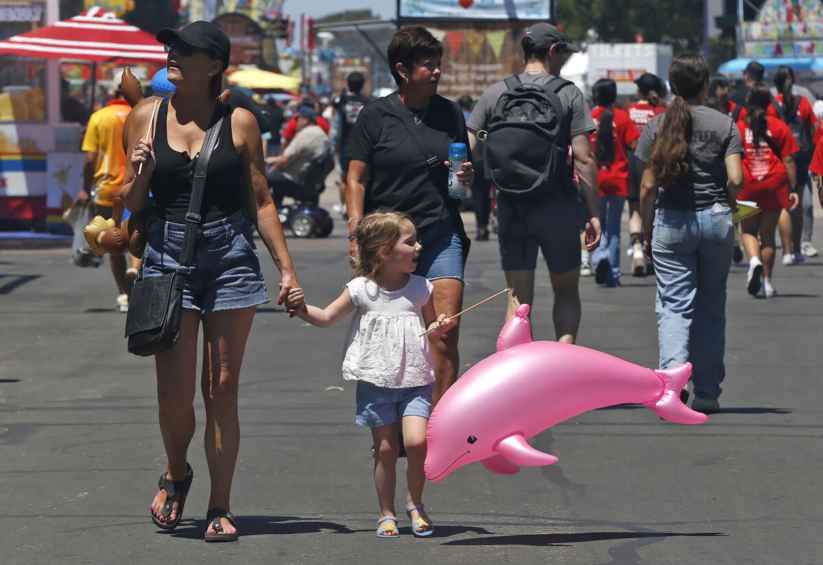 Guests walk and browse the midway on opening day of the 2023 Orange County Fair. 