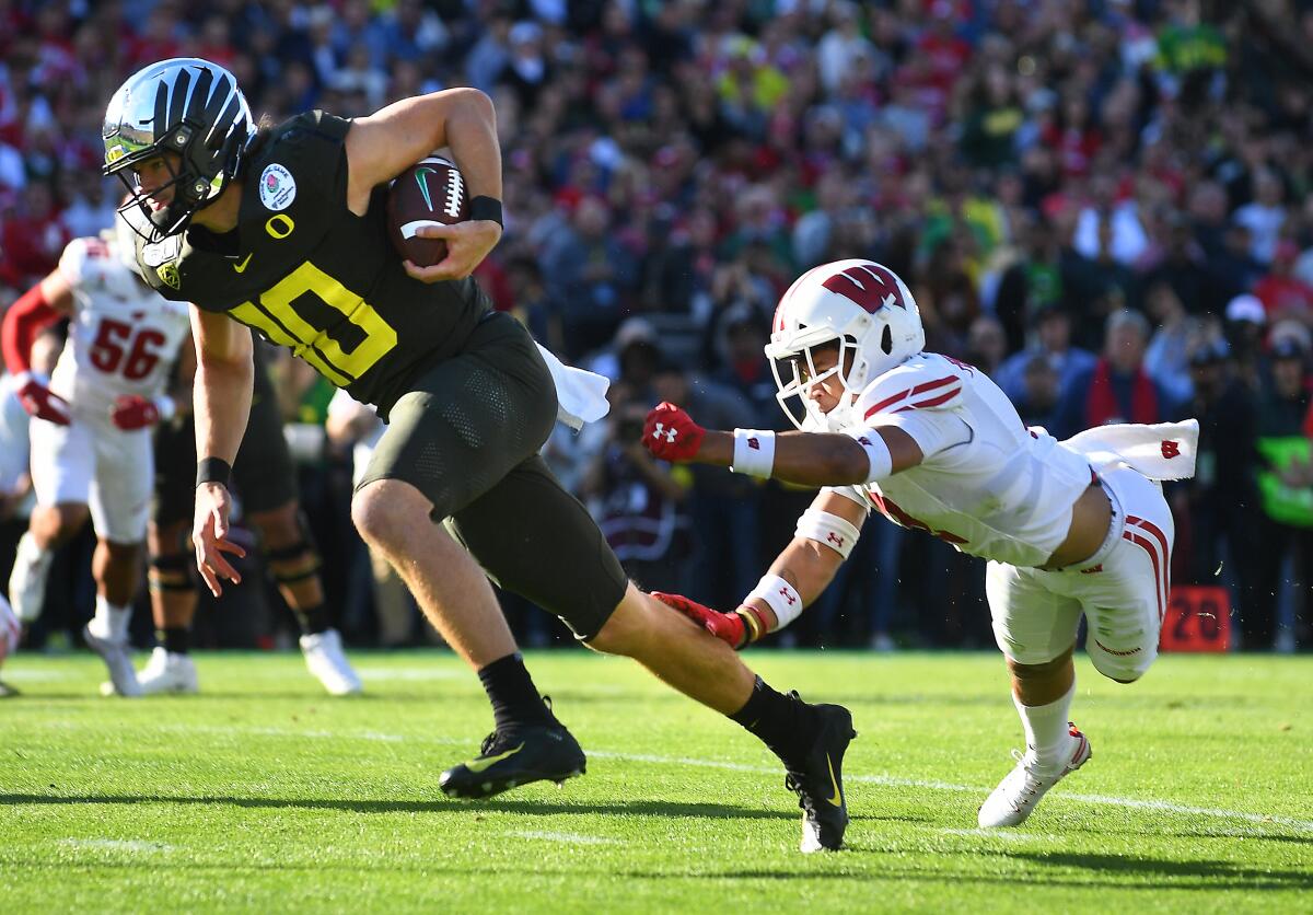 Oregon quarterback Justin Herbert breaks loose from Wisconsin safety Reggie Pearson to score a touchdown during the first quarter of the Rose Bowl. 
