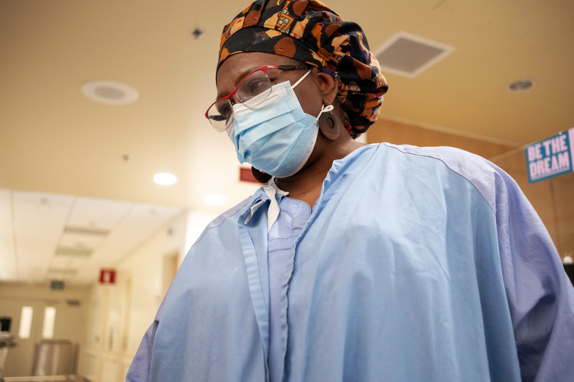 A woman in nursing scrubs and a surgical mask.