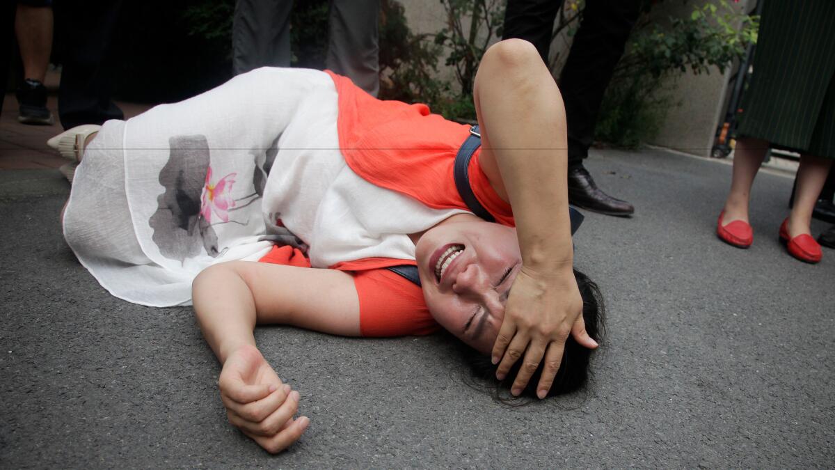 Fan Lili, the wife of imprisoned lawyer Gou Hongguo, lies on the ground in tears following an interaction with a plainclothes police officer outside the Tianjin No. 2 Intermediate People's Court in Tianjin, China, on Aug. 1.