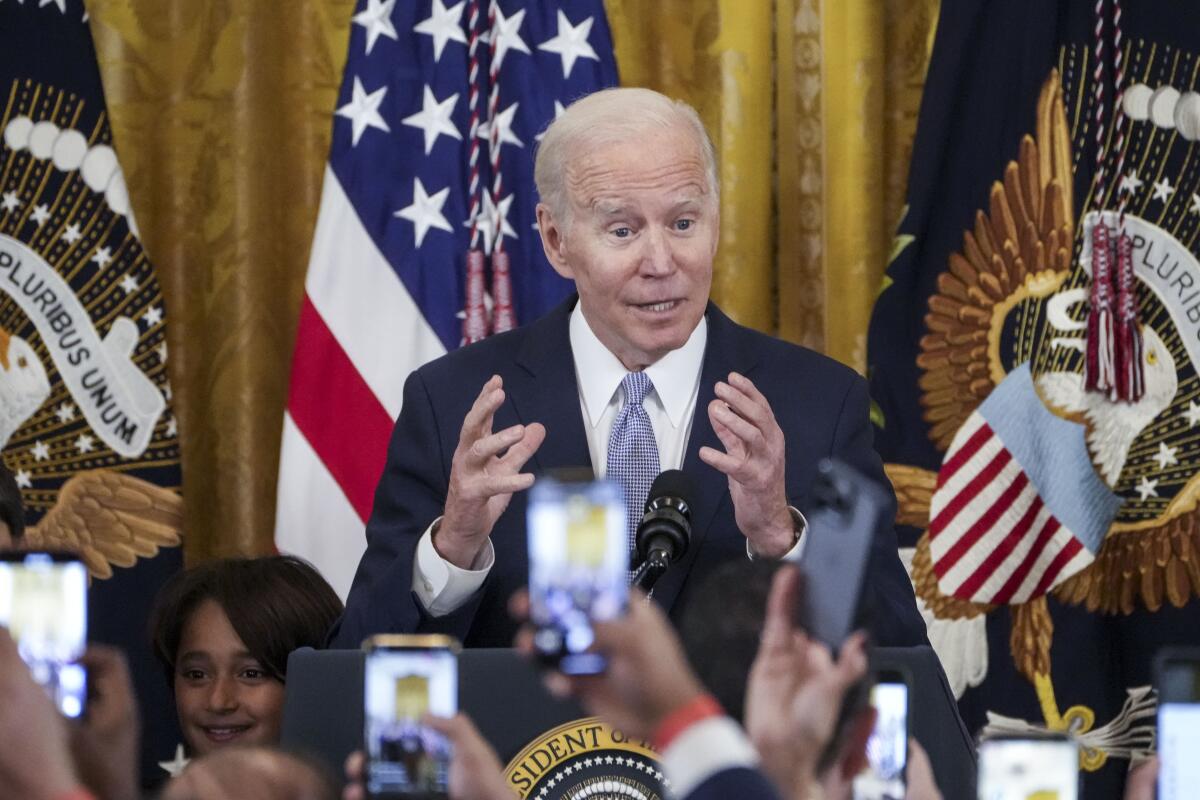 People raise their cellular phones as President Biden speaks at the White House 