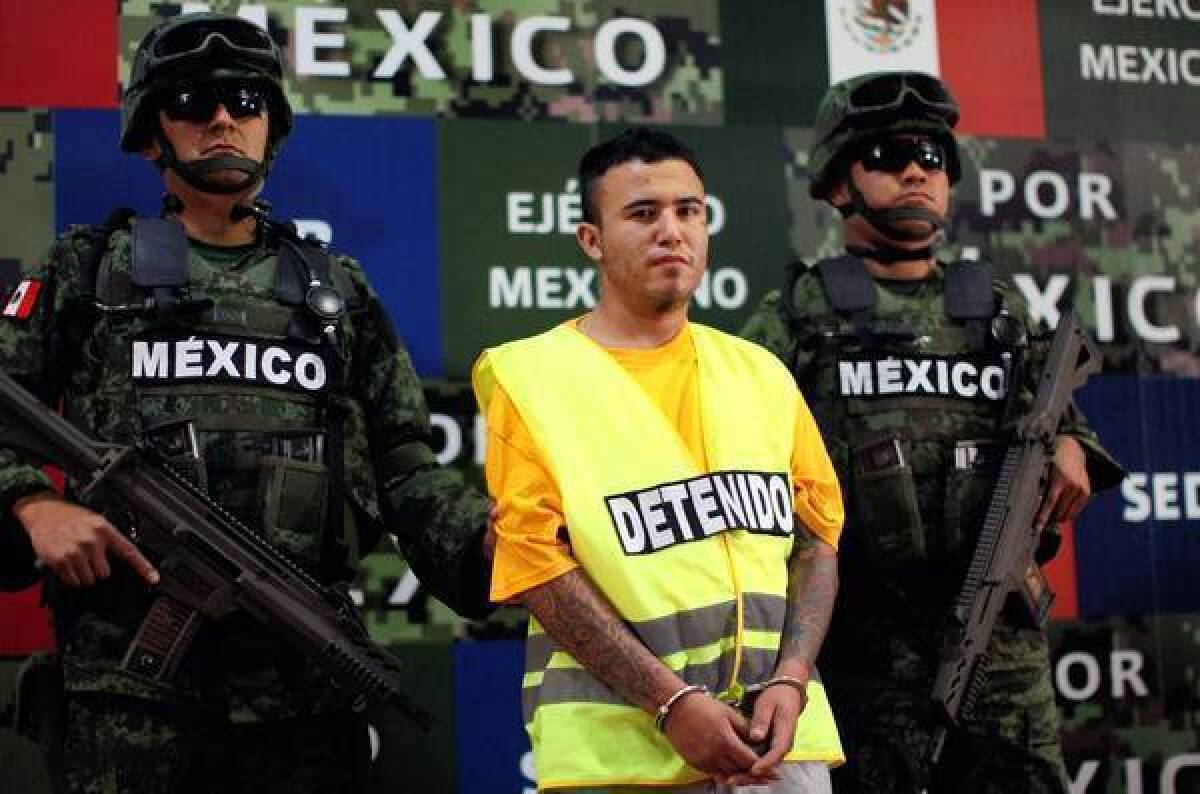 Mexican soldiers flank Daniel "El Loco" Ramirez during his presentation to the news media in Mexico City this month. Ramirez is believed to be a member of the Zetas drug cartel, which authorities suspect of dumping 49 mutilated bodies near Monterrey.