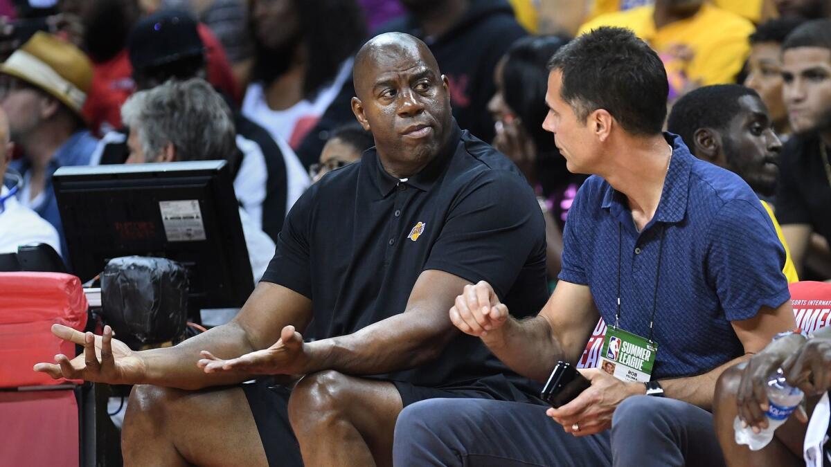 Magic Johnson, the Lakers' president of basketball operations, and Rob Pelinka, the team's general manager, sit courtside at the first NBA Summer League game in Las Vegas on July 7.
