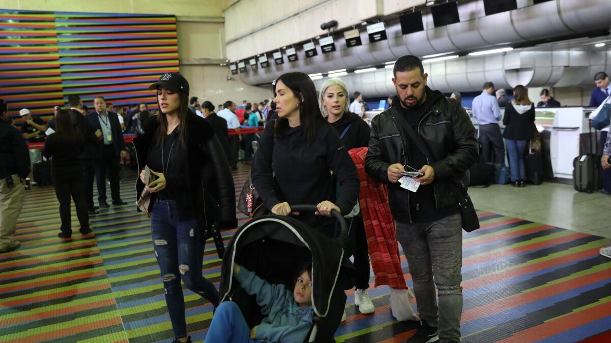 U.S. diplomatic employees and their families prepare to depart Simon Bolivar International Airport near Caracas, Venezuela.