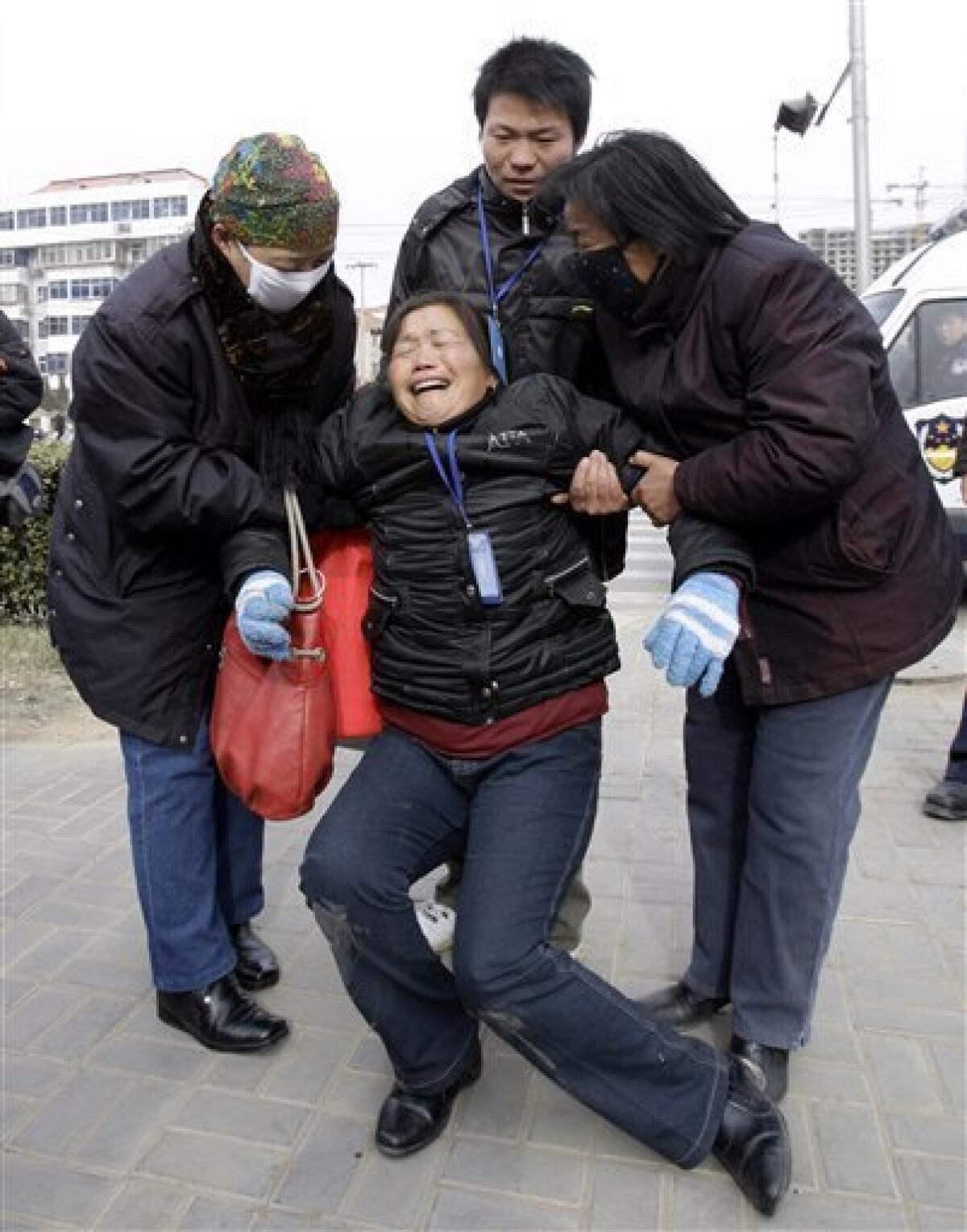 Zheng Shuzhen, center, the grandmother of a baby who died after drinking tainted milk, is supported by friends as she cries outside the Intermediate People's Court in Shijiazhuang, in China's Hebei province Thursday Jan. 22, 2009. Verdicts and sentencing were expected at the court Thursday for 21 people charged in the tainted milk scandal. (AP Photo/Greg Baker)