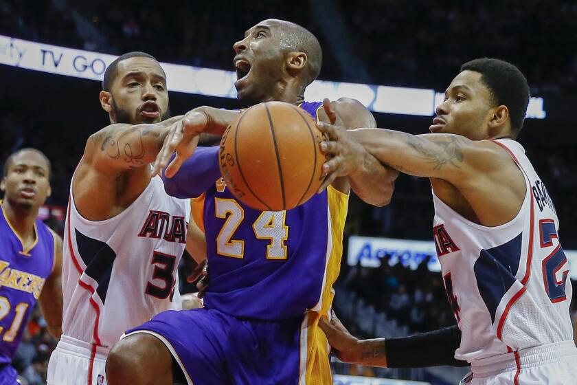 Kobe Bryant is defended by Atlanta forward Mike Scott, left, and guard Kent Bazemore, right, during the Lakers' 114-109, win over the Hawks.