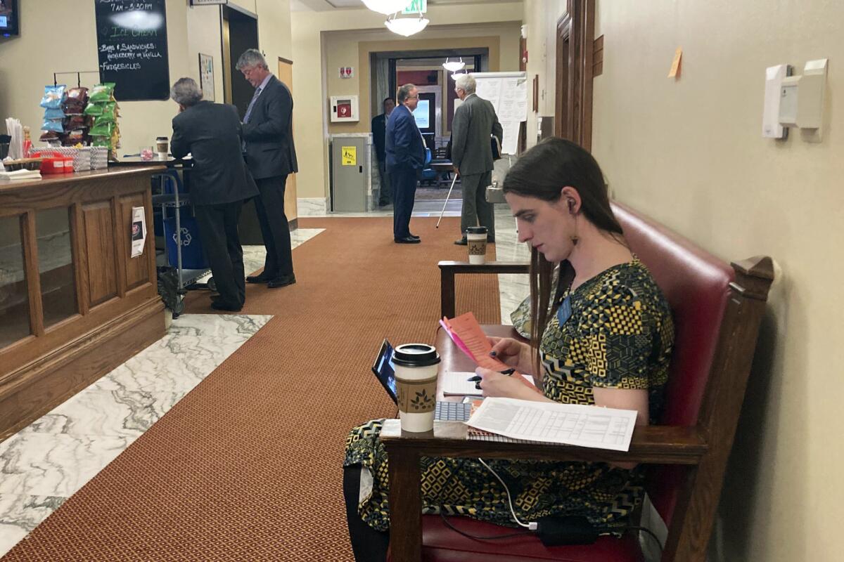 Montana state Rep. Zooey Zephyr sits in a couch in a hallway just outside the main chamber of the House.