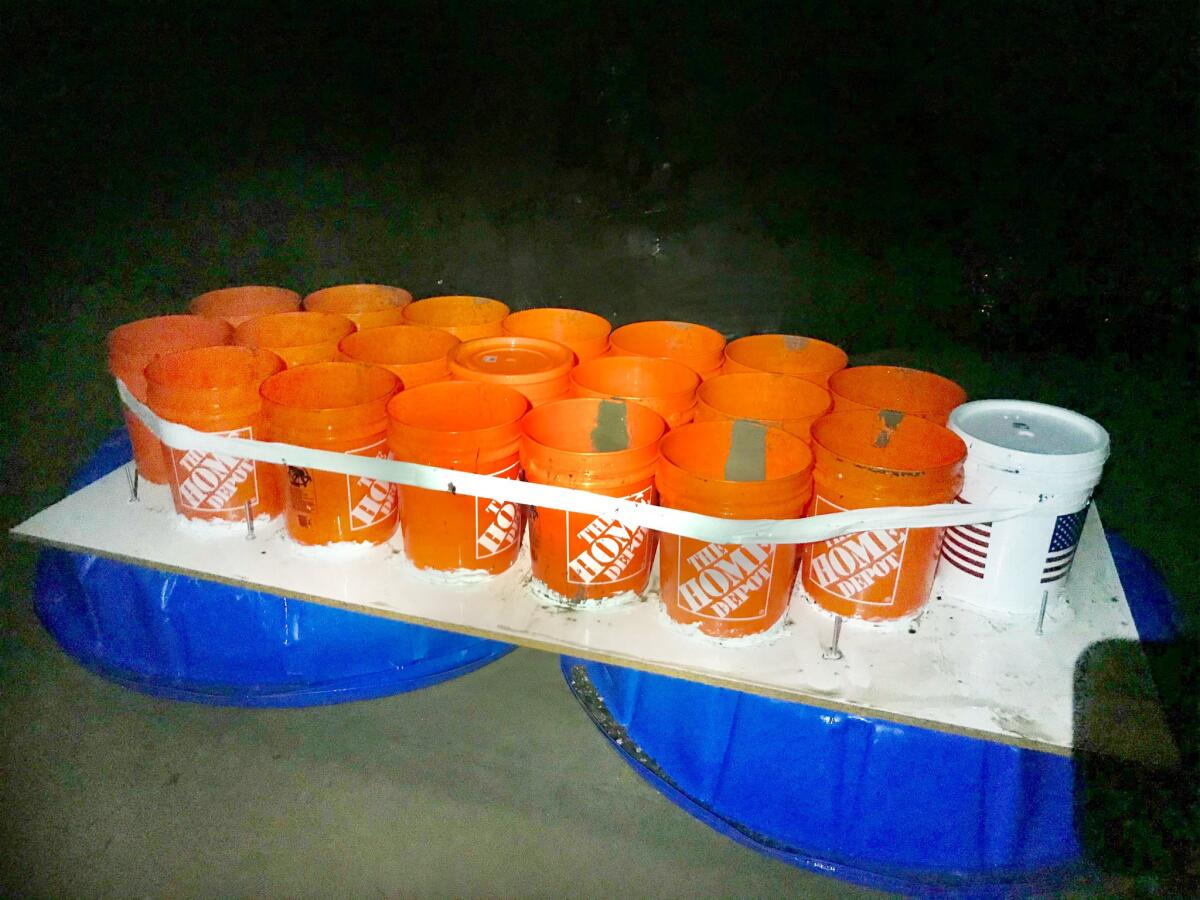 Buckets are taped together and sit on a plywood board on top of two kiddie pools.