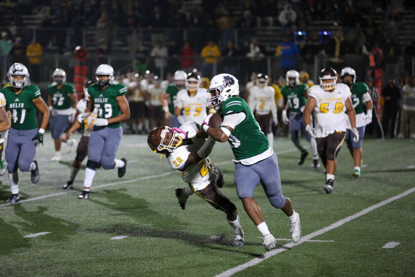 Christian Washington of the Helix HIghlanders stiff arms a defender on his way to a first down. Helix downed the El Camino Wildcats, 28-17