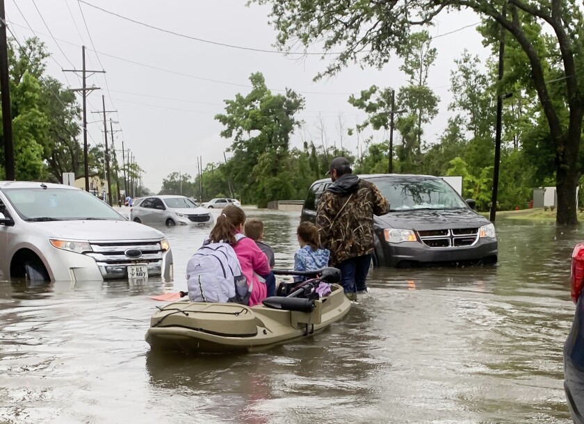 Parents use boats to pick up students from schools after nearly a foot of rain fell in Lake Charles, La., Monday, May 17, 2021. (Rick Hickman/American Press via AP)