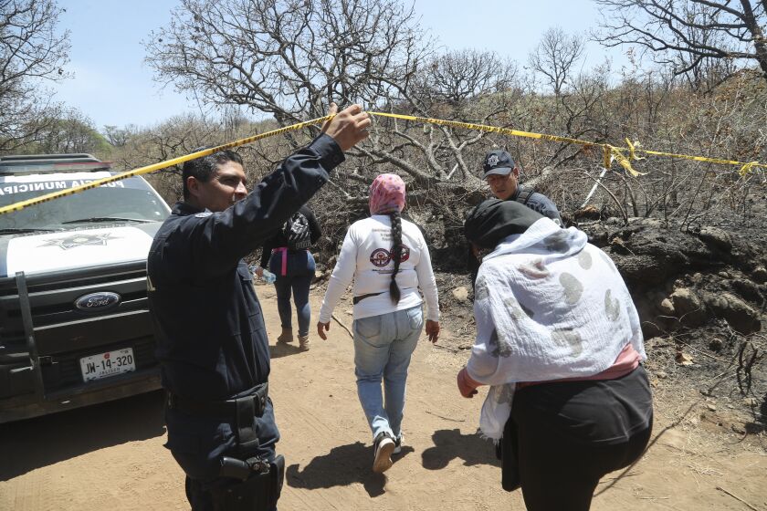 FILE - A police officer allows members of the group Madres Buscadoras de Jalisco who found several sets of human remains after receiving an anonymous tip in Tlajomulco, Jalisco state, June 14, 2023. A drug cartel bomb attack on July 11, 2023 that allegedly used a fake report of a mass grave to lure police into a deadly trap has had devastating collateral damage: It has led authorities in Jalisco state to abandon the volunteers who search for some of Mexico’s 110,000 missing people. (AP Photo/Refugio Ruiz, File)