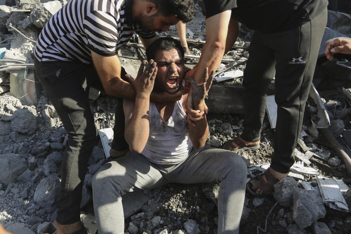 Palestinos consuelan a un hombre que llora después de perder a familiares por bombardeos de Israel 