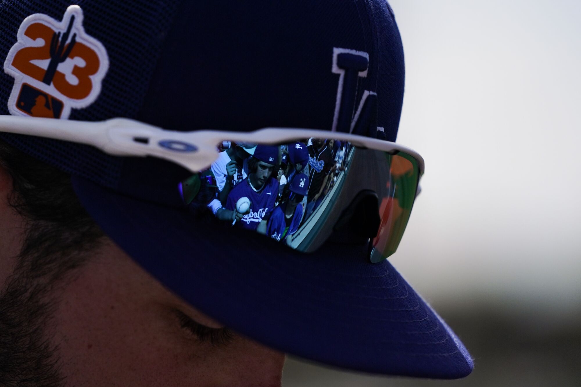 Fans holding baseballs are reflected in sunglasses of Dodgers pitcher Nick Nastrini on March 18, 2023, in Glendale, Ariz.