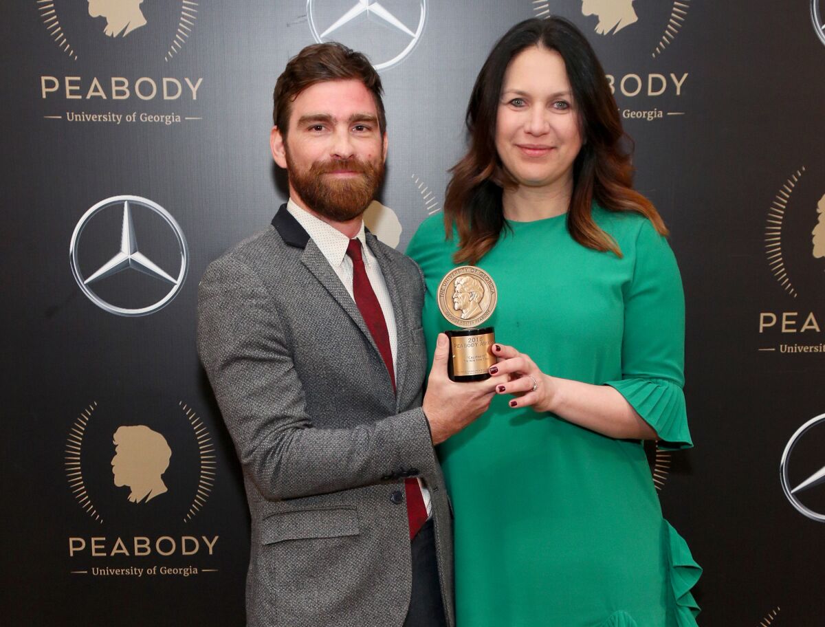Andy Mills and Rukmini Callimachi holding a Peabody Award