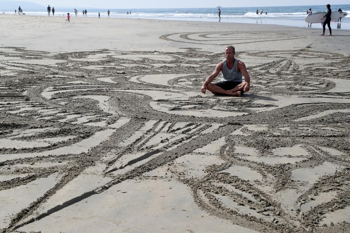 Shane Kern meditates at the center of a public art piece by Low Tide Aliens at Newport Beach Pier July 30.