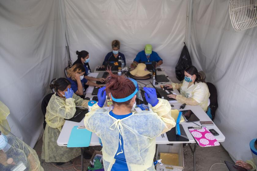 BOYLE HEIGHTS, CA - APRIL 29: Alta Med Health Services staff puts on PPE prior to COVID-19 testing on Wednesday, April 29, 2020 in Boyle Heights, CA. (Brian van der Brug / Los Angeles Times)