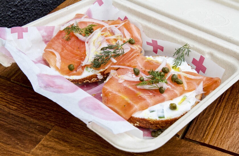 A photo of an open-faced bagel, each half topped with lox, cream cheese, capers, onion and dill.