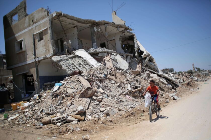 A Palestinian boy rides his bicycle past buildings that were destroyed during the 50-day war between Israel and Hamas militants in the summer of 2014.