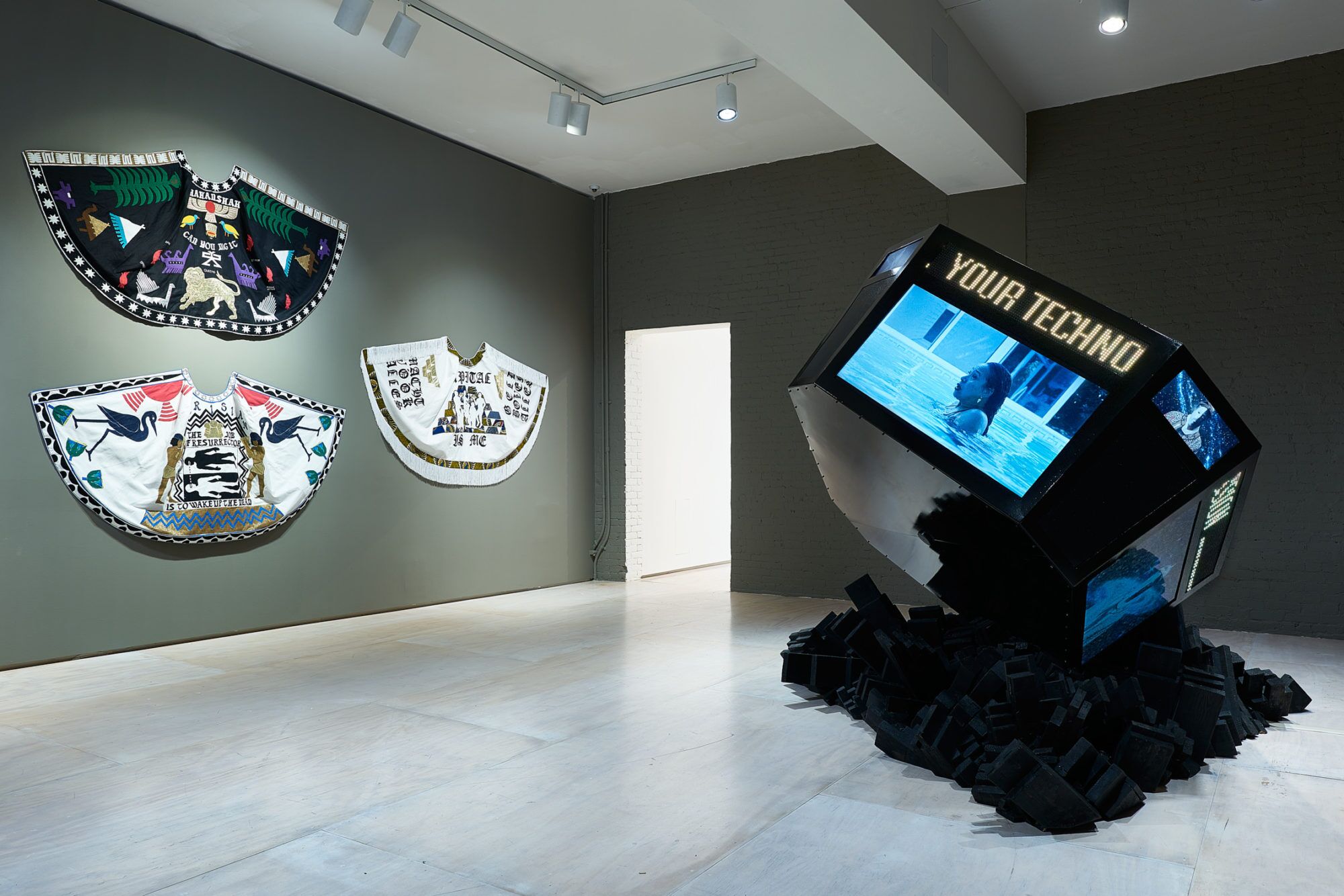 A gallery view shows capes pinned to a wall and a Jumbotron type object looking as if it crashed into the floor.