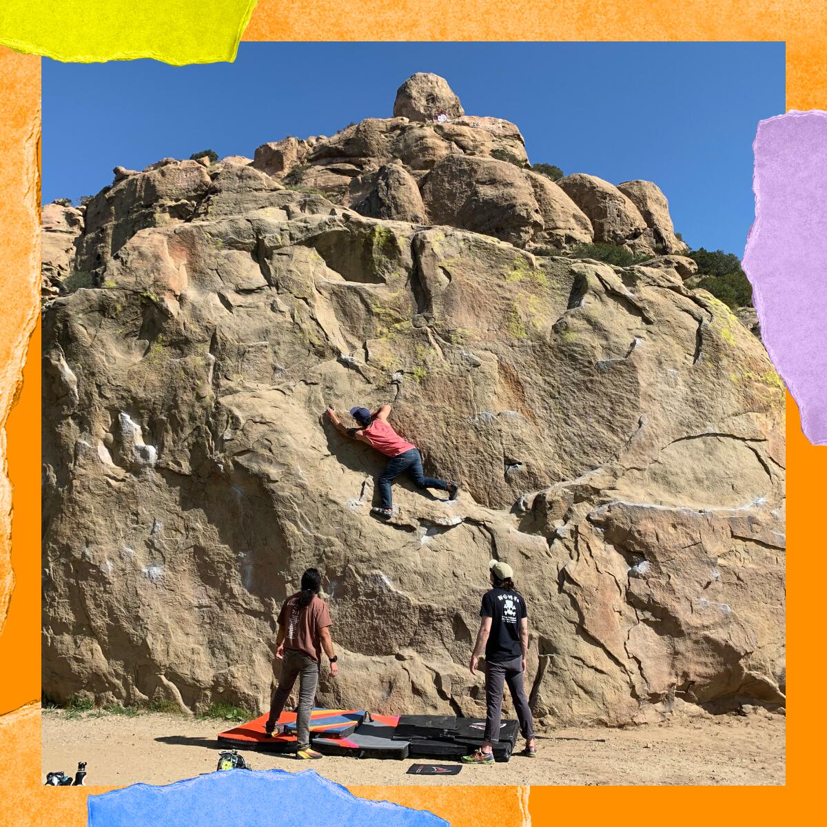 A group of three people, with one climbing a large rock and two others standing below.