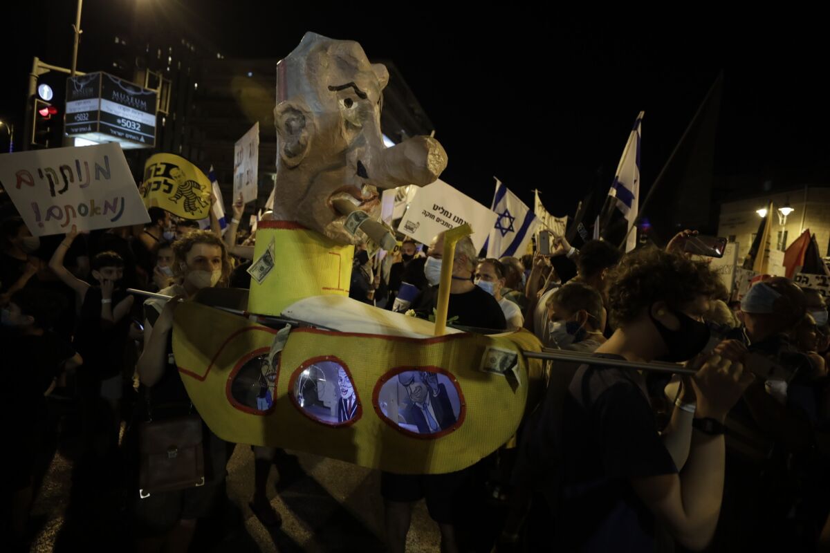 Israelis hold signs and chant slogans during a demonstration against Israeli Prime Minister Benjamin Netanyahu near the Prime Minister's residence in Jerusalem, Saturday, Aug. 15, 2020. (AP Photo/Sebastian Scheiner)