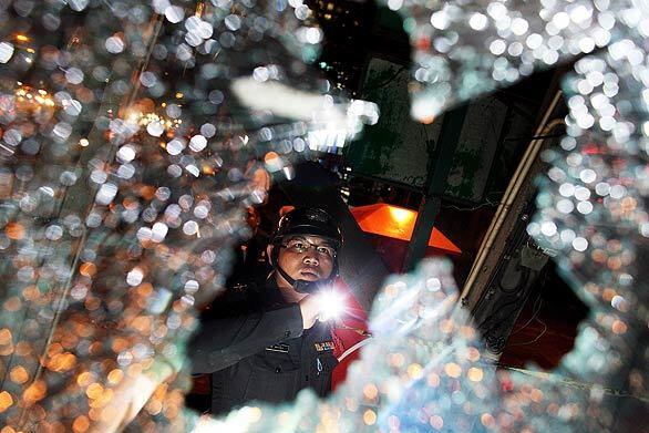 A Thai police officer inspects the damage after anti-government demonstrators swarmed Bangkoks international airport. The protesters clashed with government supporters in an escalation of the countrys long-running political crisis.