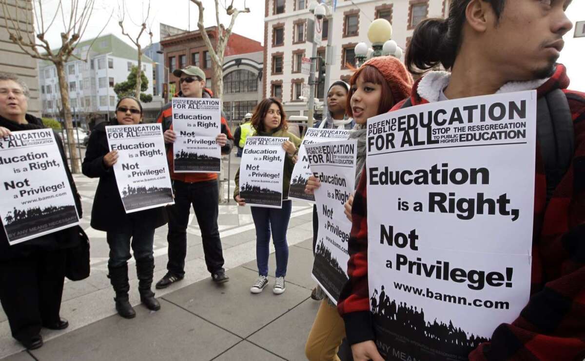 Protesters hold signs that say "Defend public education for all" and "Education is a right, not a privilege!"