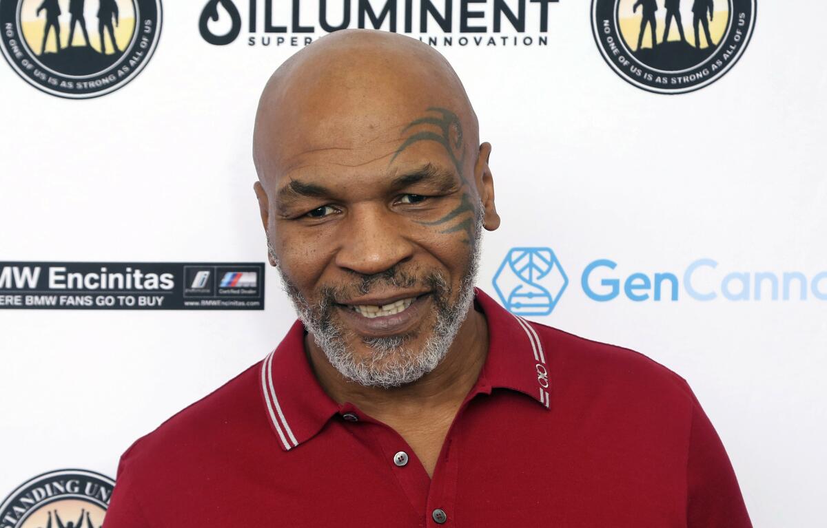 Mike Tyson smiles in a red polo shirt.