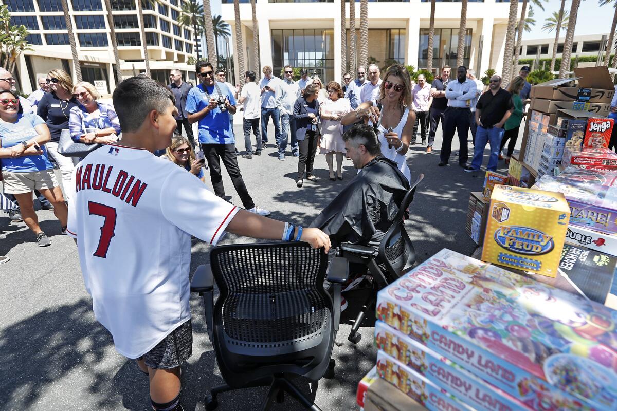 Zachary Maudlin, left, looks on as Komron Tarkeshian gets his head shaved. Maudlin passed the clippers to Eleni Dalis, Tarkeshian's personal hairstylist, after he started feeling bad for shaving Tarkeshian's head.