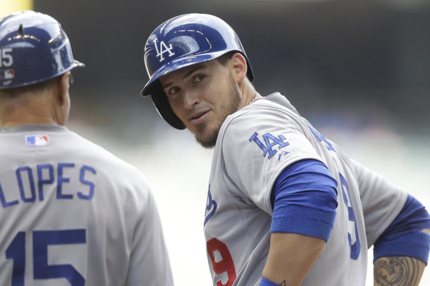 Dodgers catcher Yasmani Grandal, right, speaks with first base coach Davey Lopes after hitting a two-run single against the Milwaukee Brewers on May 7.