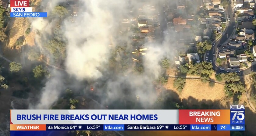 Aerial view of smoke and a brush fire near a residential neighborhood