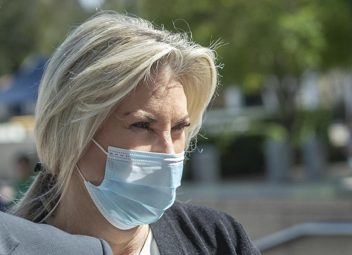 A woman with blond hair, wearing a blue mask 