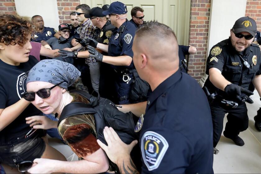 Protesters scuffle with police during a rally in front of Graham Memorial Building on the campus of UNC in Chapel Hill, N.C., Saturday, Aug.25, 2018. The rally featured those for and against the removal of the controversial "Silent Sam" statue which was toppled earlier this week. (Chuck Liddy/The News & Observer via AP)