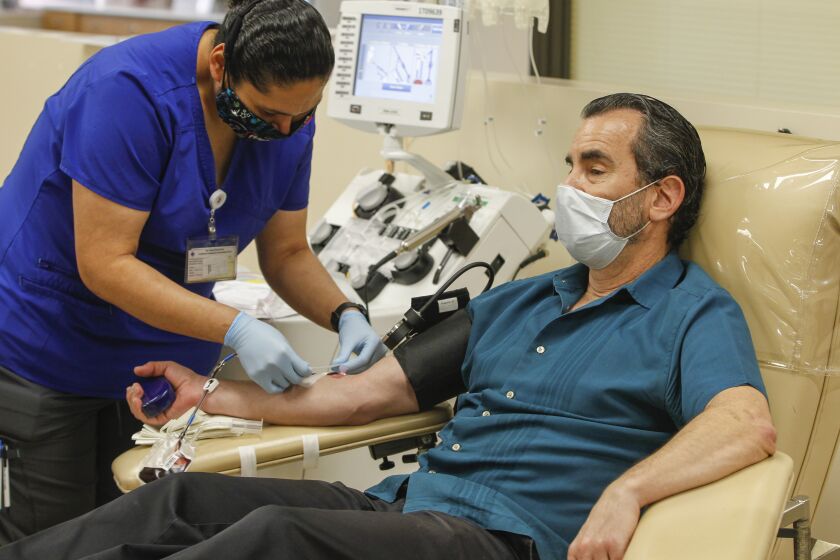 Dan Galant (right) makes his plasma donation with donor technician Leya Ramos (left) at the San Diego Blood Bank on May 6, 2020 in San Diego, California. Galant had a blood test and he tested positive for antibodies that could be used to treat COVID-19 patients.