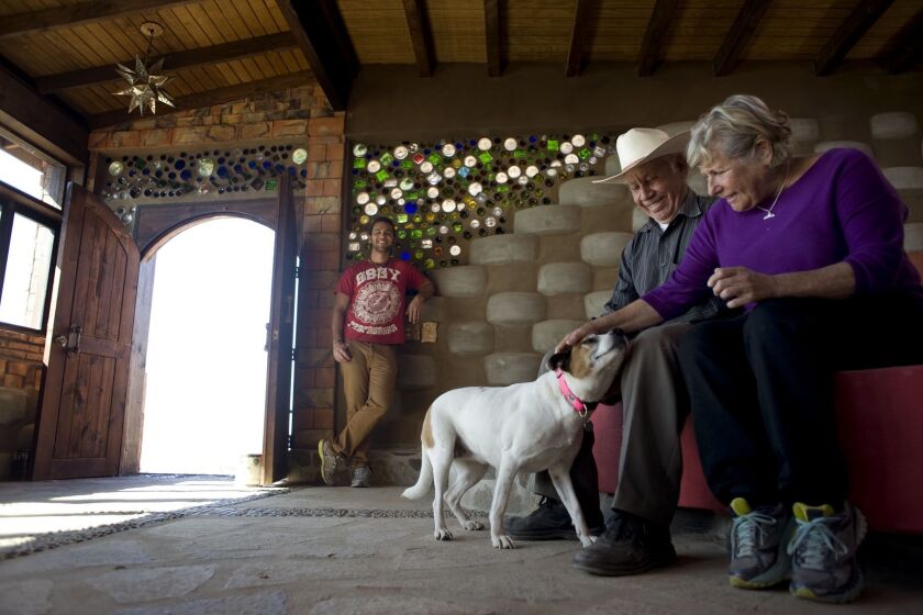 Sandra Moffat and construction foreman Jose Lara greet Moffat's dog Piedra inside the Rosarito Beach house she had built of recycled materials. In the background is the architect, Diego Colinas.