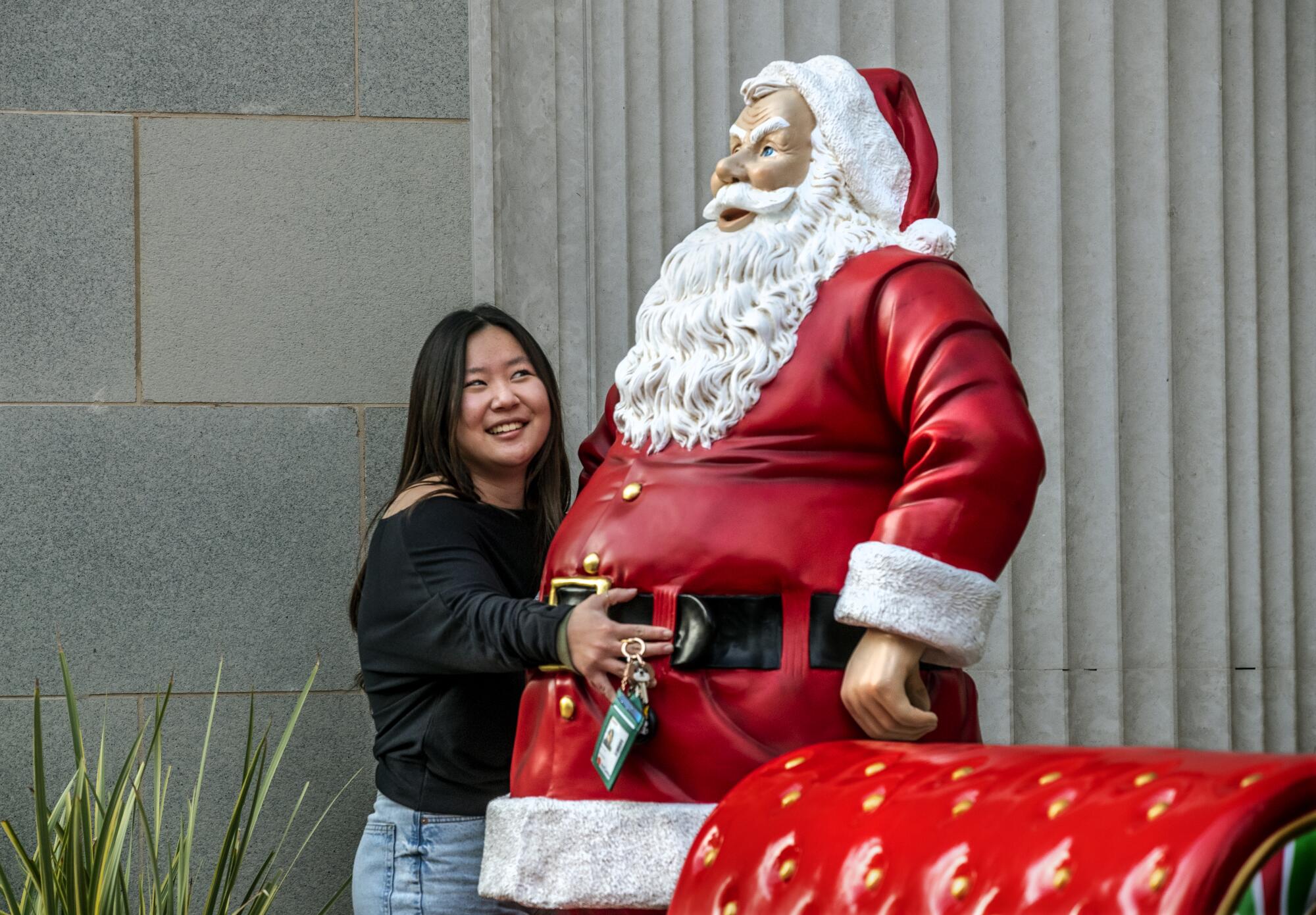 BEVERLY HILLS, CA-DECEMBER 16, 2022: Taylor Baik, 19, of Pasadena, hugs a Santa Claus statue
