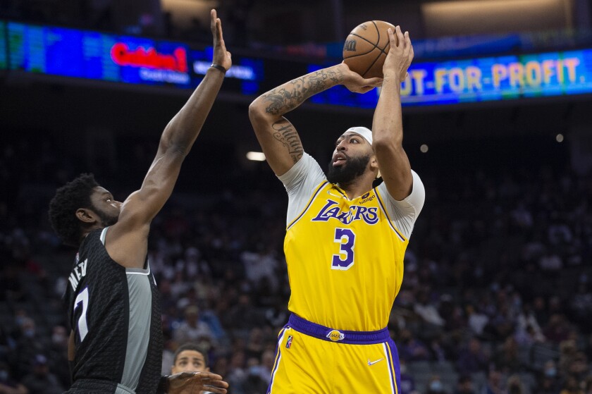 El jugador de los Lakers de Los Ángeles Anthony Davis (3) lanza a canasta ante su rival de los Kings de Sacramento Chimezie Metu (7) en el primer cuarto del juego de la NBA que enfrentó a ambos equipos, en Sacramento, California, el 30 de noviembre de 2021. (AP Foto/Randall Benton)