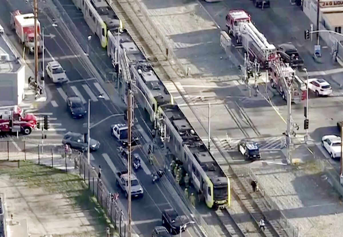 A train stopped on tracks surrounded by first responders and emergency vehicles